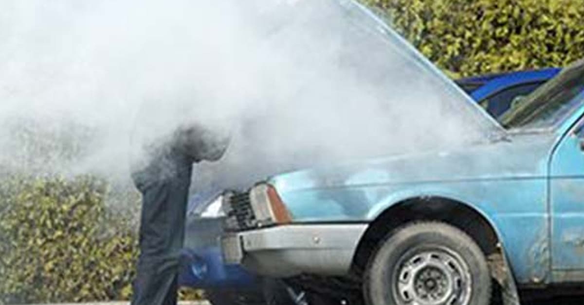 scrap car broken down with smoke coming from the engine