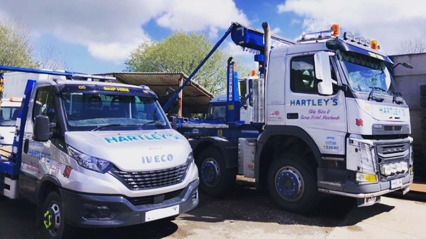 Hartley’s blue and orange skips available for hire in Stoke-on-Trent and Staffordshire, lined up outside the skip hire yard.